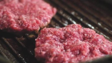 yağ parçaları ile iki sulu et çiğ kırmızı Burger köftesi yapışmaz kaplama ile sıcak demir ızgara tavada kızartılır. Kaynayan zeytinyağında. sprey ve buhar. ev mutfağında pişirme makro fotoğraf