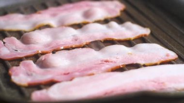 koyu sıcak dökme demir ızgara tavada yapışmaz kaplama ile yavaş yavaş domuz pastırması dört yağ, sulu lezzetli dilimlenmiş ince dilimkızartma. buhar ve duman çok. Ev mutfağında yemek pişirmek. Yavaş çekim yakın çekim.