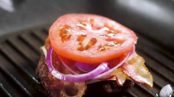 新鲜的芝麻包子落在一圈红熟番茄上 有炸棕色的帕蒂和一块方形的薄白融化奶酪和脆片的培根 制作汉堡包的过程 — 图库视频影像