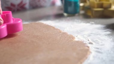 şekerlemeci güçlü bir kalp şeklinde plastik pembe bir kalıp üzerine parmaklarını bastırır ve beyaz un üzerinde yatan bir haddelenmiş ince kahverengi hamur bir kıvırcık çerez keser. Panoramik yakın çekim