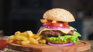 sulu kızarmış pirtidar, taze marul, peynir ince dilim, soğan ve domates bir cam Bardak patates kızartması ve sos yanında pişmiş hamburger panoramik atış. Arka planda Mutfak.