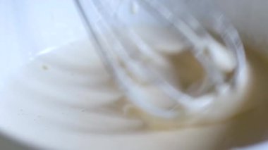 pasta şefi krem beyaz el çırpıcı kırbaçlar. Kaldır. sıvı sos ahşap masa üzerinde duran derin plaka içine ince dere aşağı akar. Kek pişirme için pişirme malzemelerinin sürecinin yavaş çekim yakın çekim
