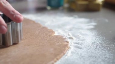 kadın pasta metal kalıp karşı parmakları presler ve beyaz un üzerinde yatan hamur ince kahverengi dışarı haddelenmiş kurabiye rakam keser. panorama çekimi