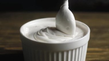 pasta şefi küçük bir kaşık la ahşap bir masa üzerinde derin bir Fincan kalın bir beyaz krem karıştırır. Kıvırcık bir kıvrım oluşturarak kıvırcık kıvırcık oluştururken kıvırcık kadar kepçe ve kaldırır.