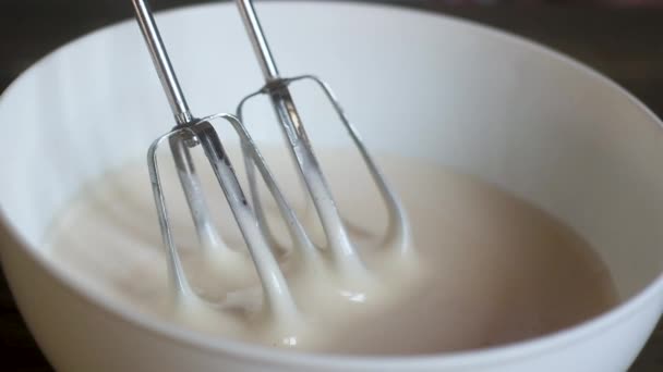 糖果师从一个装有白色液体奶油的大杯子中拉出电动搅拌机的铁刀片 酱汁慢慢流下来 特写拍摄 — 图库视频影像
