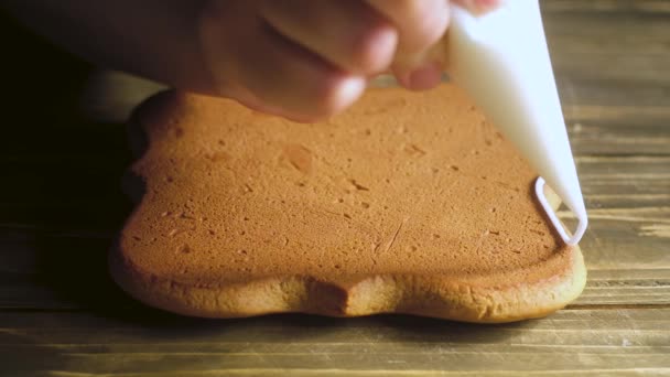 菓子屋は 焼きたての茶色の巻き生姜の上に細い線で白いクリームを絞ります シェフはクッキーの輪郭を作ります ケーキの装飾 — ストック動画
