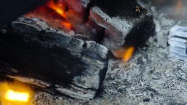 yanan siyah kömürler yakın çekim. Rüzgar gri kül ve duman puluçup gider. Ahşabın kenarı küçük bir alevle yanar..
