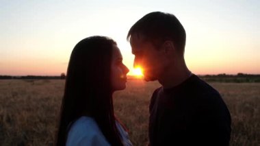 Yaz günbatımında öpüşen genç bir çift. Güneşin altında bir erkek ve bir kadının silueti. Doğada romantik bir ilişki. geleneksel aşk.