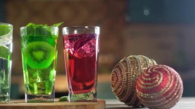 ferahlatıcı gazlı kokteyllerin panoramik yakın çekim. bir nane yaprağı ve kivi ve buz küpleri, Fesleğen ile kırmızı bir kokteyl, kireç cam dilimleri ile berrak köpüklü su ile. Şenlikli içecekler