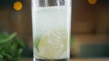 köpüklü berrak su alt taze kireç dilimleri ile uzun bir cam bardak içine dökülür. Bir sürü baloncuk çıkıyor. Kamera yukarı doğru hareket ediyor. meyve float parçaları.