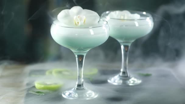Glas Glasögon Med Blå Cocktail Och Vit Orkidé Blomma Står — Stockvideo