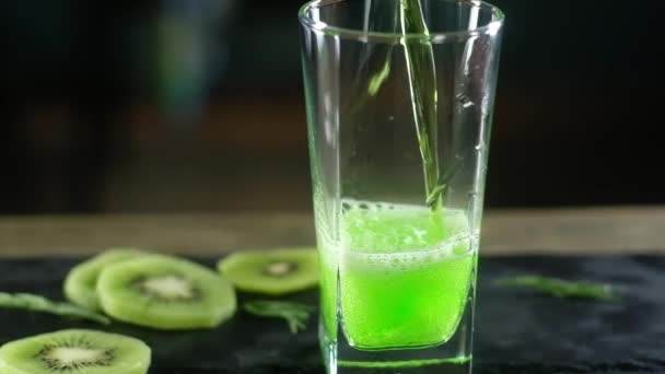 Зеленый Газированный Напиток Наливают Стекло Кружка Сидит Подносе Ломтиками Киви — стоковое видео