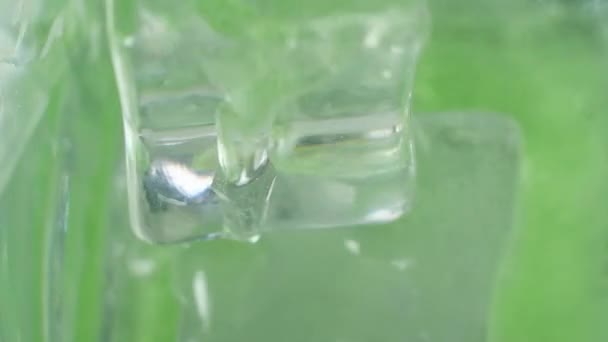 绿色的鸡尾酒倒入杯子里 那里有几块冰冷的冰块 饮料滴落 气泡和飞溅 宏观模式 从上而下的角度 一个有趣的派对的开始 工作室照明 — 图库视频影像