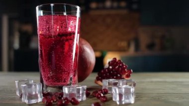 Soğuk buz küpleri ile şeffaf bir cam kırmızı gazlı kokteyl Panoramik Shot. Yakında olgun nar ve pembe tahıllar ve buz kristalleri vardır. yavaş çekim
