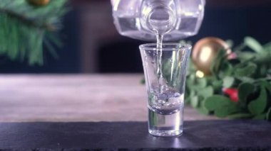 barmen küçük bir şeffaf bardağa bir şişe soğuk alkollü içecek döker. Noel sezonu. Şenlikli süslemeler ve oyuncaklar etrafında. Yeni Yılınız Kutlu Olsun.