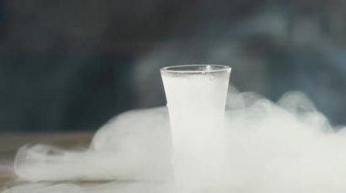 buzlu bir bardak votka donmuş cam tepside boş oturur. buhar ondan kaçar ve ahşap masa boyunca yayılır.