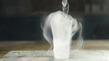 soğuk buhar yavaş yavaş buz ile kaplı sisli cam yukarıdan düşüyor. camdan standa büyük su damlaları akar. Studio ışık ile yavaş hareket