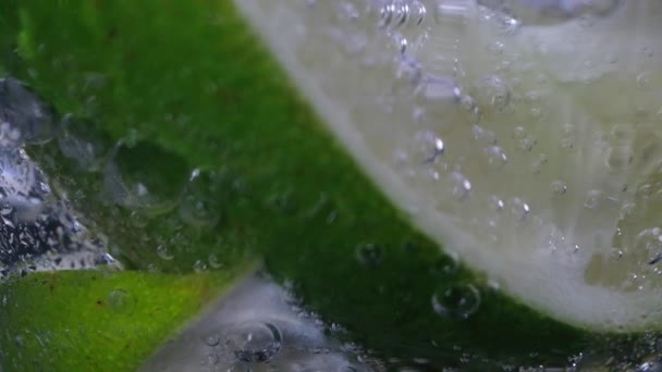 Einem Glas Sprudelnden Wassers Schwimmen Saftige Limettenstücke Bewegt Sich Die — Stockvideo