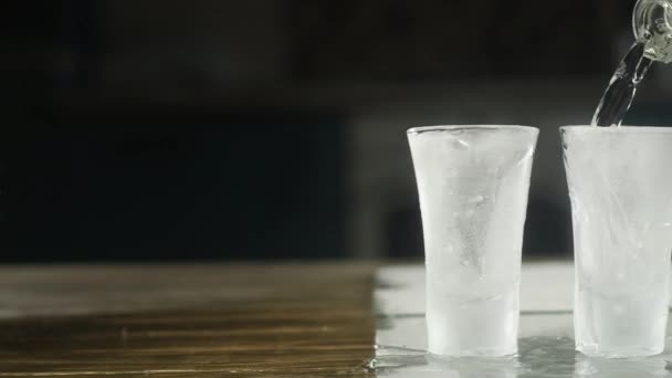 Plan Panoramique Verser Vodka Une Bouteille Dans Plusieurs Verres Glacés — Video
