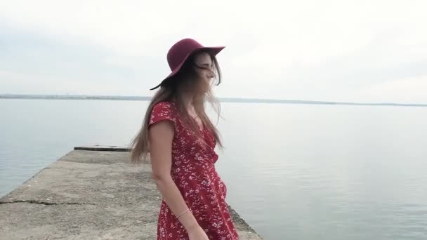 Mujer Con Pelo Largo Vestido Rojo Sombrero Oscuro Encuentra Muelle — Vídeo de stock