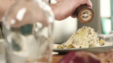 Soslu İtalyan makarnası pişirmek. Pişirmek, karabiber kokulu biber ve biber karıştırmak. Akşam yemeği için lezzetli bir yemek. Adam evdeki mutfakta yemek pişiriyor ve bir tabağa baharat ve baharat döküyor.