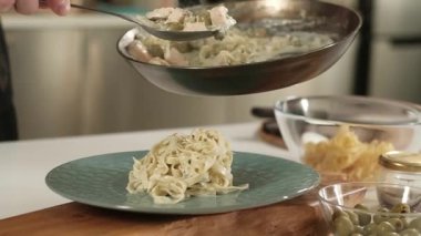Soslu İtalyan makarnası pişiriyorum. Profesyonel bir aşçı evin mutfağında bir tabak krema soslu ve deniz mahsullü spagetti koyar. Bir adam evdeki mutfakta yemek pişiriyor.