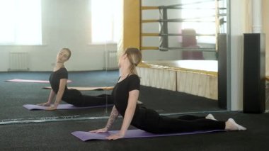 Çekici fitness kızı, vücudun kaslarını ayna karşısında germek için egzersiz yapıyor. Günlük sağlıklı yaşam tarzı kavramı. Stüdyoda yoga ve pilates dersleri.