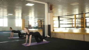 Çekici fitness kızı vücut kaslarını esnetebilmek için aynanın karşısında egzersiz yapıyor. Bir kadın bacaklarını çalıştırıyor. Günlük sağlıklı yaşam tarzı kavramı. Stüdyoda yoga ve pilates dersleri