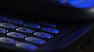 Klavyedeki eski cep telefonlarının makro atışları. Eski, çizilmiş, tozlu cep telefonları mavi neon ışıkta masanın üzerinde duruyor. Ofiste analog iletişim. Modern kablosuz teknoloji