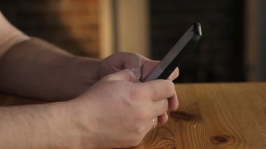 Yetişkin bir adam işyerindeki bir ofiste oturuyor ve akıllı telefondan bir mesaj yazıyor. Bir adamın cep telefonundaki bir numarayı parmaklarıyla tuşlarken yakın plan fotoğrafı. Modern kablosuz teknoloji.