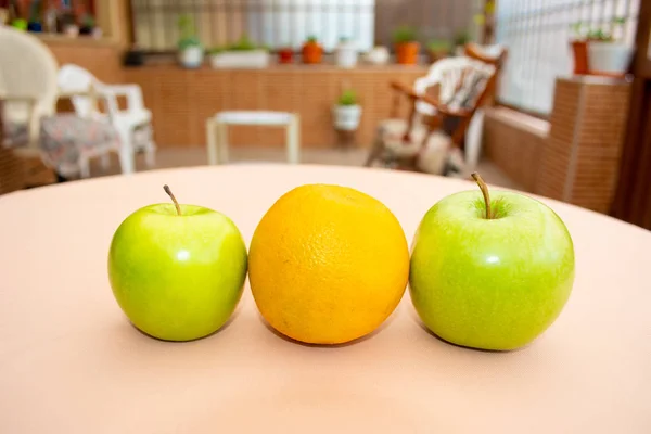 Two green apples and one orange in the middle