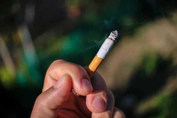 Holde på en menneskelig sigarett mens man røyker, ikke røyke, helsehjelp – stockfoto