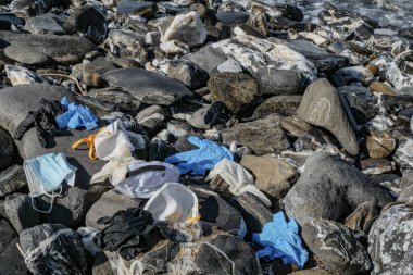 Tıbbi atık, Virüs maskesi ve plastik eldivenler kayalık deniz kıyısına atılan çöpler, koronavirüs 19 kirlilik 