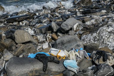 Tıbbi atık, Virüs maskesi ve plastik eldivenler kayalık deniz kıyısına atılan çöpler, koronavirüs 19 kirlilik 