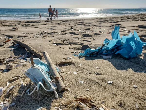 Tıbbi atık, Virüs maskesi ve plajdaki plastik çöpler, plajda oynayan insanlar, koronavirüs 19 kirliliği 