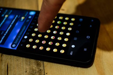 Adam emoji simgelerine göz atıyor ve onları dinliyor, akıllı telefon mesajlaşma ifadeleri simgesi