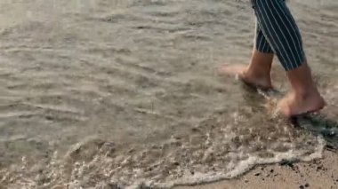 Kristal deniz suyunda yürüyen kız ayaklarının yavaş hareketi, özgürce karantina