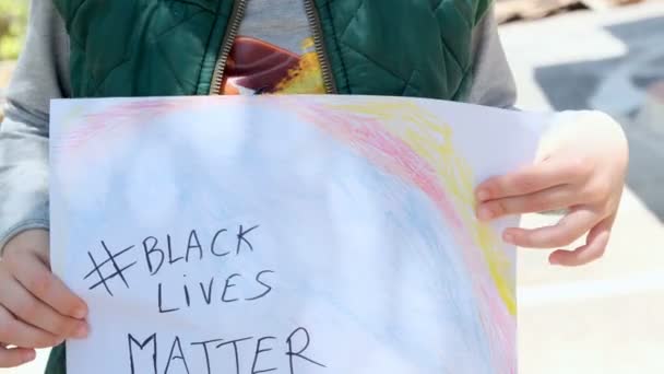 Ребенок держит краску для поддержки черных жизни материи протеста в США, нет расизма — стоковое видео