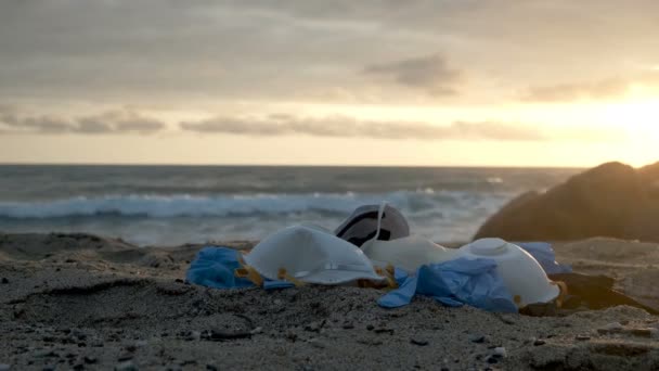 Medicinsk virusmask och plasthandskar, avfall från solnedgången vid havet, coronavirus — Stockvideo