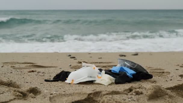 Маска и пластиковые перчатки медицинские отходы на берегу моря, вирус ковидового загрязнения — стоковое видео