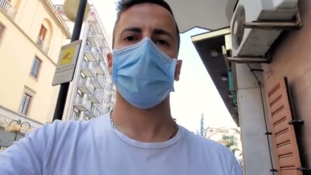 Ung man promenader aroung stad med coronavirus skyddande mask, covid19 sjukdom — Stockvideo