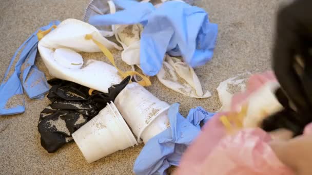 Mann greift nach Maske und Plastikhandschuhen am Meeresufer, Coronavirus medizinische Abfallverschmutzung — Stockvideo