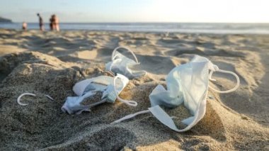 Deniz kıyısında yürüyen insan geçmişine sahip atık tıbbi yüz maskeleri, kovid19 virüs salgını 