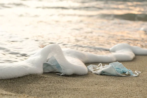 Mascarillas médicas desechadas en espuma de mar al atardecer, covid19 pandemia de contaminación por enfermedades —  Fotos de Stock