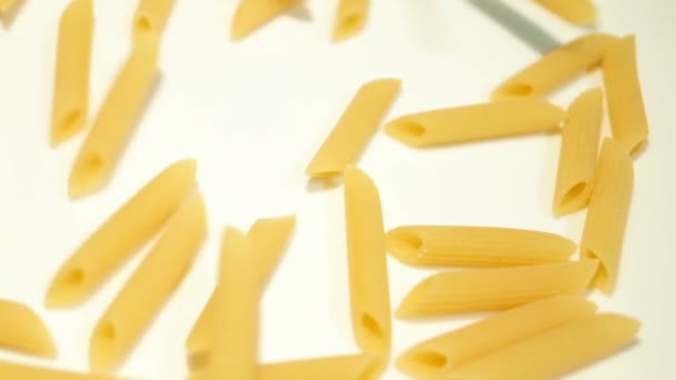 Неварені макарони пенне, що падають на білу поверхню повільний рух, кухонне харчування фону — стокове відео