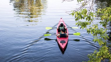 Nehirde kayak yapan bir çift. Turistler, yaz günü göl kenarında kano turu yapan kadın ve erkekler. Geriye dönüp bakıldığında, aile seyahati konsepti. Aktif dinlenme, su sporları eğlencesi..
