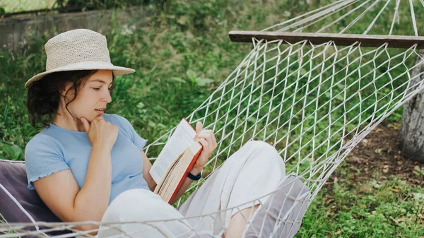 Bedachtzame Jonge Vrouw Zomer Strohoed Lezen Interessant Boek Een Hangmat — Stockfoto