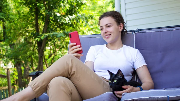 Jovem mulher sorrindo e rindo enquanto envia mensagens de texto em um  telefone em casa mulher alegre conversando com seus amigos com aplicativos  rolando mídias sociais e assistindo memes engraçados da internet enquanto  relaxa em um sofá