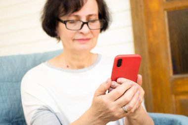 Modern akıllı telefonu elinde tutan, haberleri ya da internet sitelerini okuyan, kablosuz internet bağlantısı kullanan, evdeki kanepede oturan son sınıf öğrencilerinin fotoğraflarını çek. Yaşlılar ve teknoloji kavramı