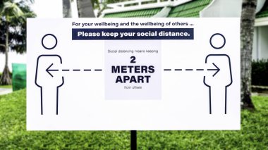 Lütfen mesafenizi koruyun. Sosyal uzaklık işaretleri, diğerlerinden 2 metre ayrı durmak anlamına gelir. Tatil köyündeki çimenlikte beyaz etiketli kelimeler.